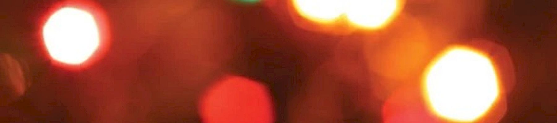The image features a blurred background of multicolored lights, creating a bokeh effect with various hues of red, green, yellow, and blue.