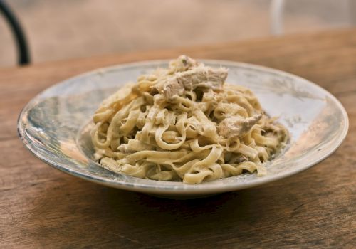 A plate of creamy pasta with mushrooms, placed on a wooden table, ready to serve.