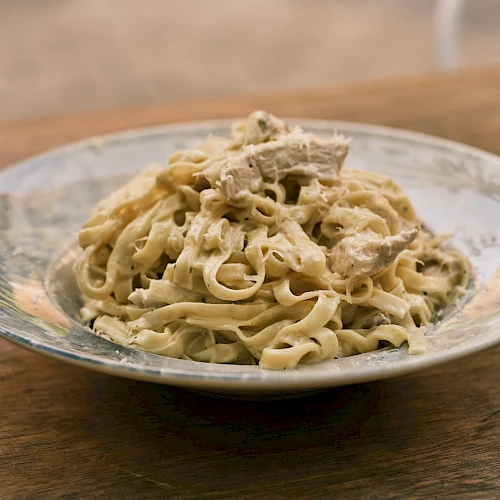A plate of creamy pasta with mushrooms, placed on a wooden table, ready to serve.
