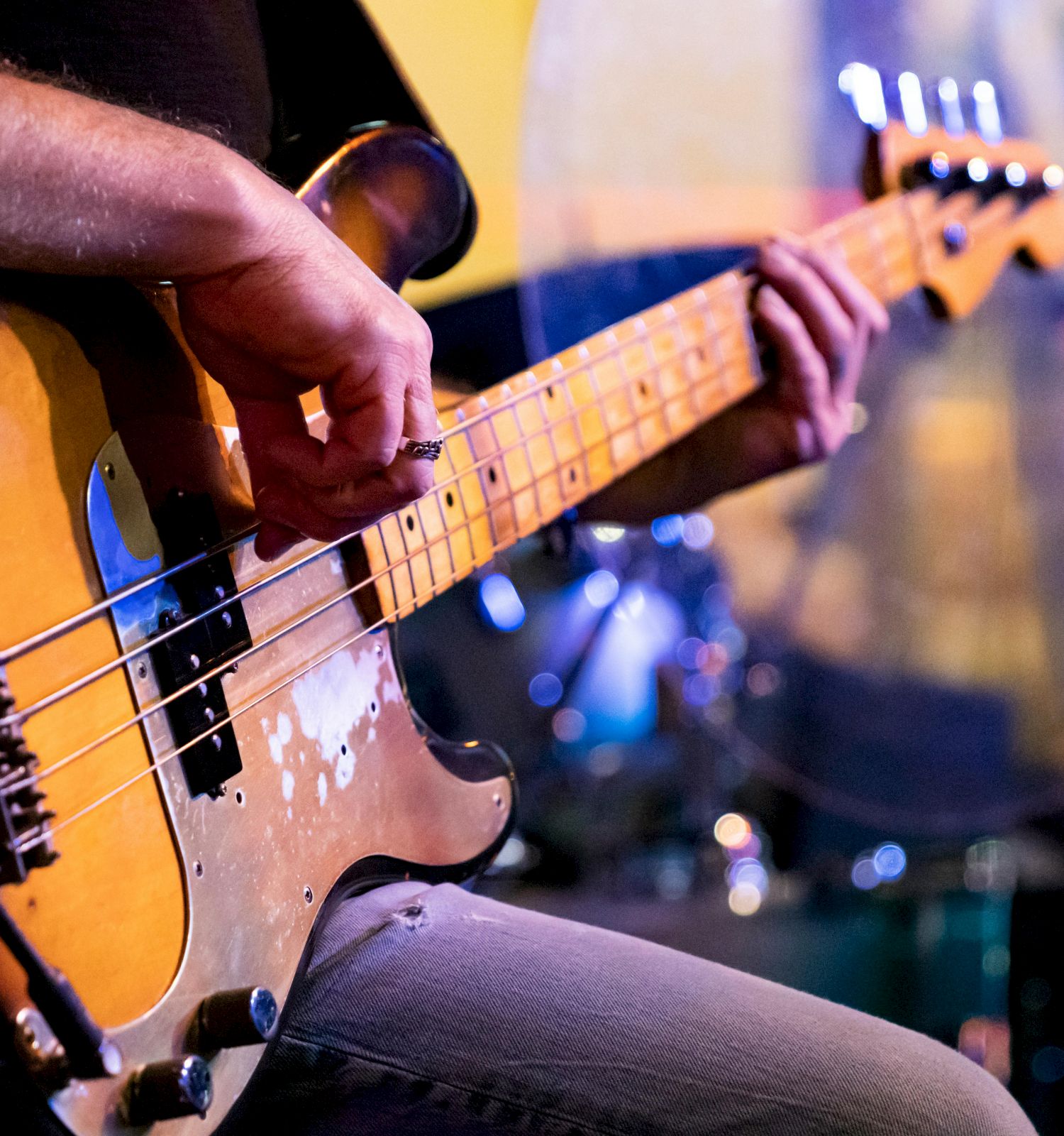 A close-up of a bass guitar being played, with a guitarist&rsquo;s hands on the neck and strings.