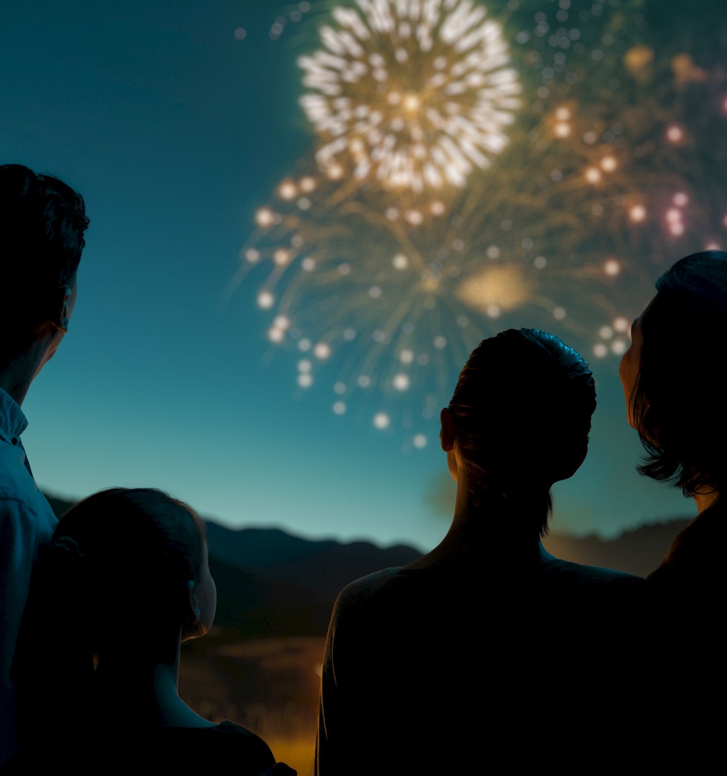 Silhouetted people watch sparkling fireworks light up the night sky, glowing in celebratory bokeh.